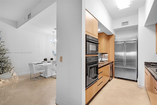 kitchen with a chandelier, appliances with stainless steel finishes, hanging light fixtures, and light brown cabinetry