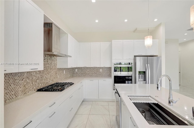 kitchen with sink, white cabinets, stainless steel appliances, and wall chimney range hood