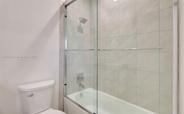 bathroom featuring toilet and bath / shower combo with glass door