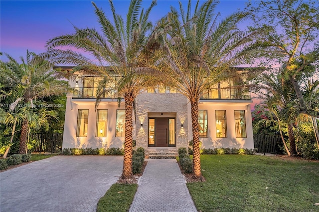 view of front of house featuring a lawn and a balcony