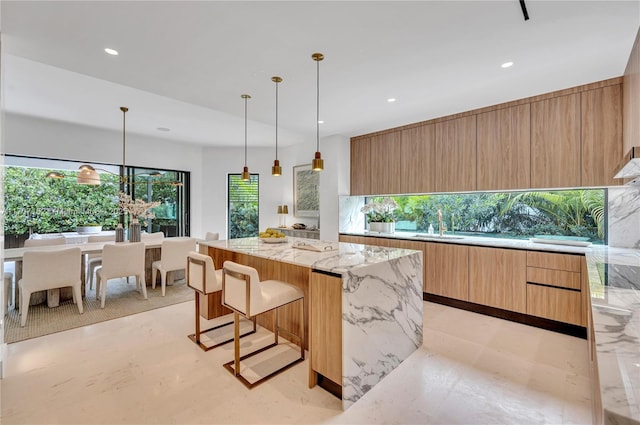 kitchen featuring light stone counters, a breakfast bar, a spacious island, decorative light fixtures, and stovetop