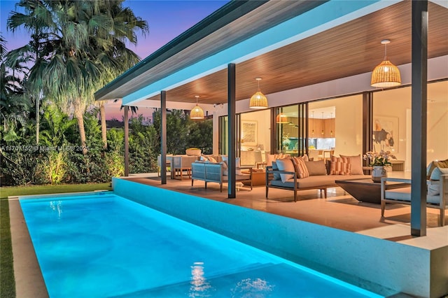 pool at dusk featuring an outdoor hangout area and a patio