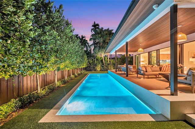 pool at dusk featuring an outdoor living space and a patio