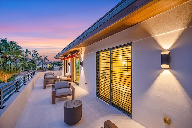 patio terrace at dusk featuring a balcony