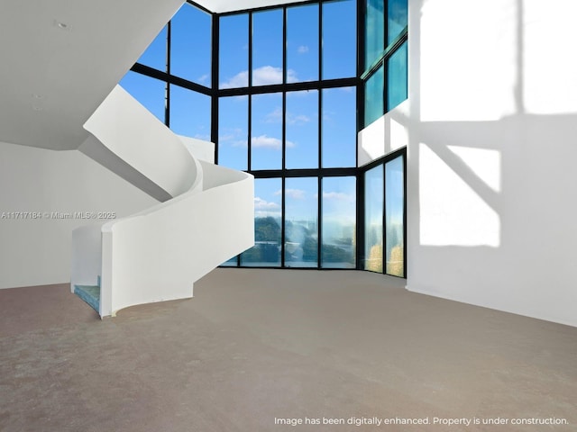 unfurnished living room featuring a high ceiling and a wall of windows