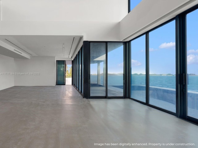 empty room with floor to ceiling windows, concrete floors, a water view, and a healthy amount of sunlight