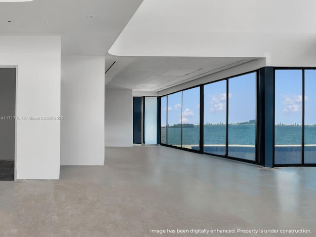 unfurnished room with floor to ceiling windows, a water view, and concrete floors