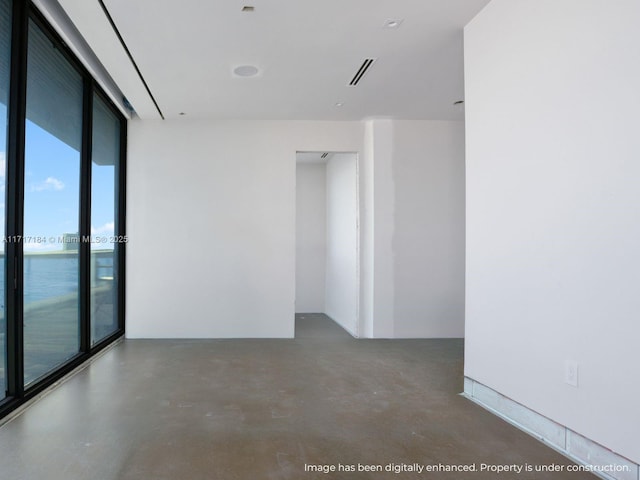 unfurnished room with plenty of natural light, a water view, concrete flooring, and a wall of windows