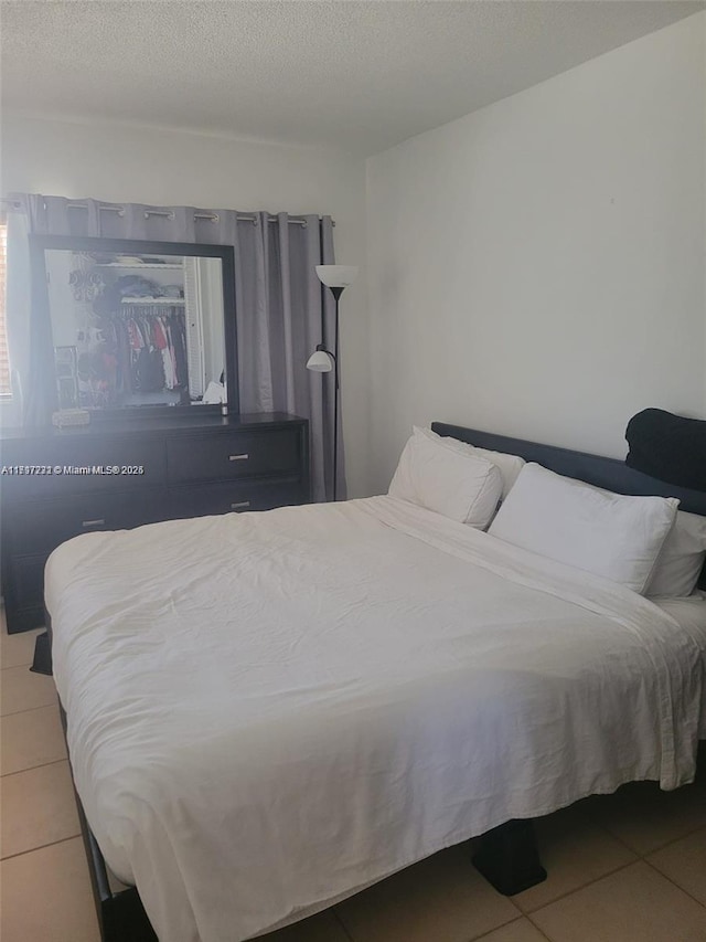 bedroom with a textured ceiling and tile patterned floors