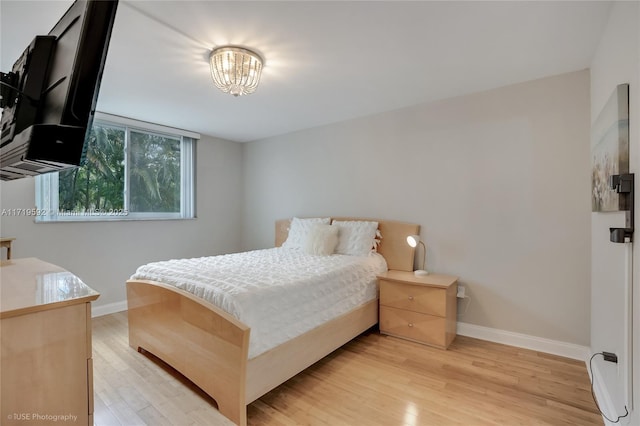 bedroom with an inviting chandelier and light hardwood / wood-style flooring