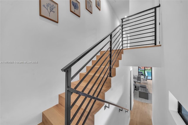 stairs featuring hardwood / wood-style flooring and a high ceiling