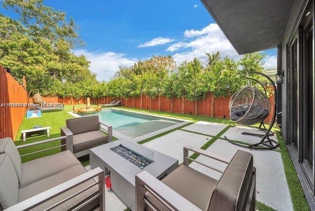 view of patio with a fenced in pool and an outdoor living space with a fire pit