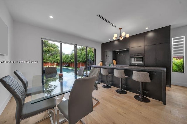 dining space with an inviting chandelier and light hardwood / wood-style flooring