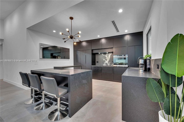 kitchen with sink, a kitchen breakfast bar, a notable chandelier, oven, and pendant lighting