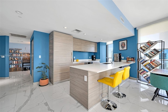 kitchen featuring a breakfast bar area, kitchen peninsula, sink, and a wall of windows