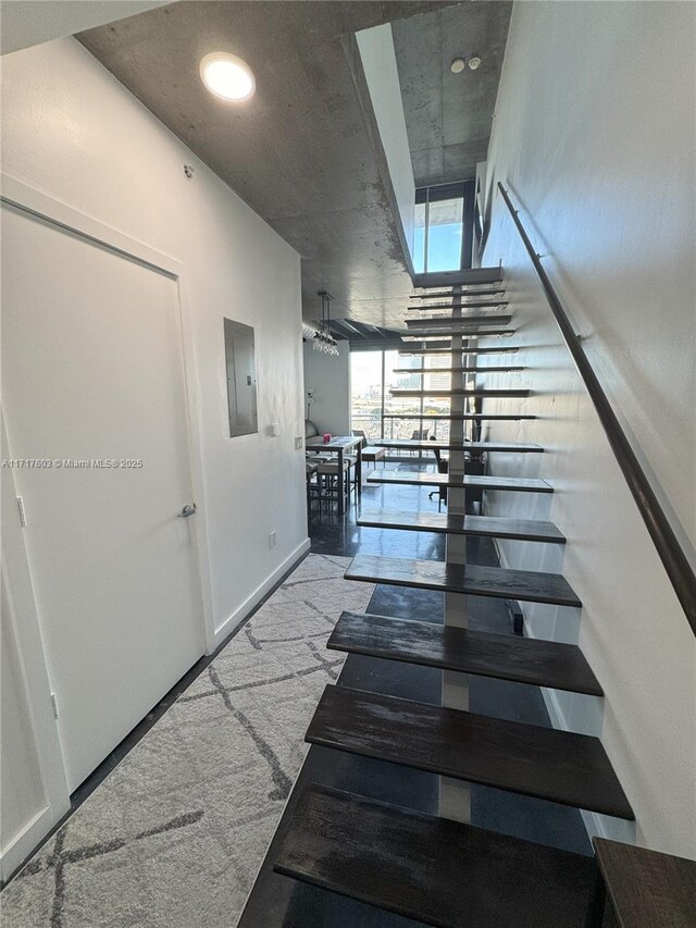 hallway featuring electric panel and light colored carpet