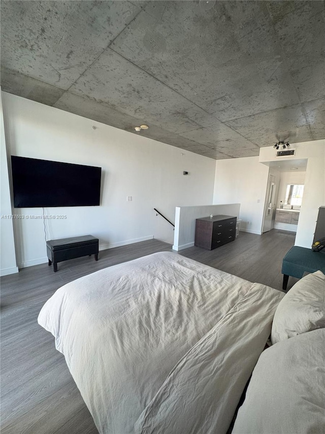 bedroom with ensuite bathroom and dark hardwood / wood-style flooring