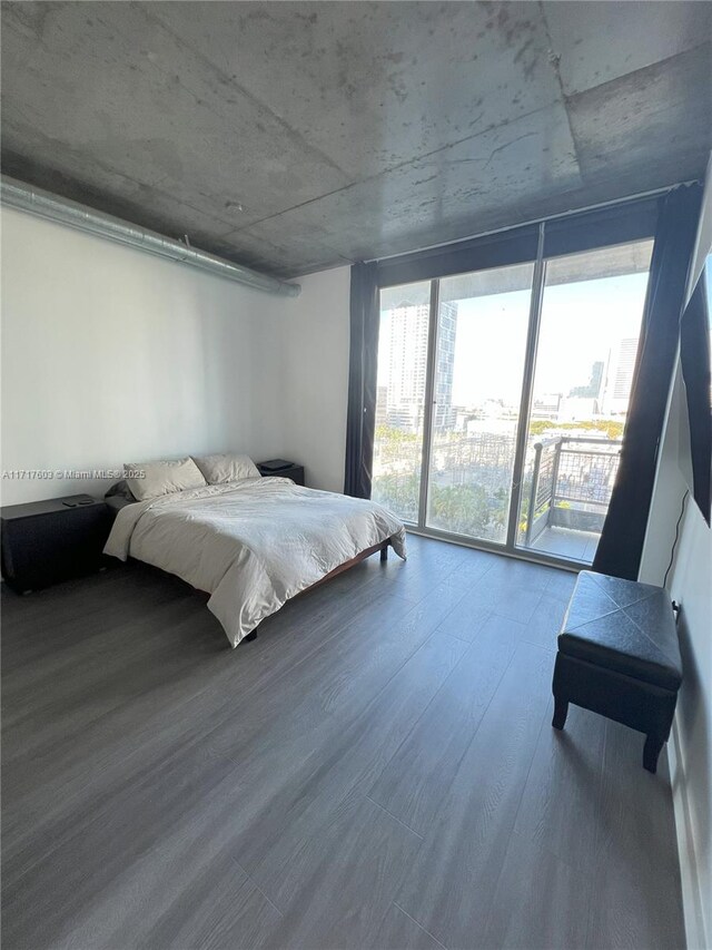 bedroom with a wall of windows, hardwood / wood-style flooring, and access to exterior