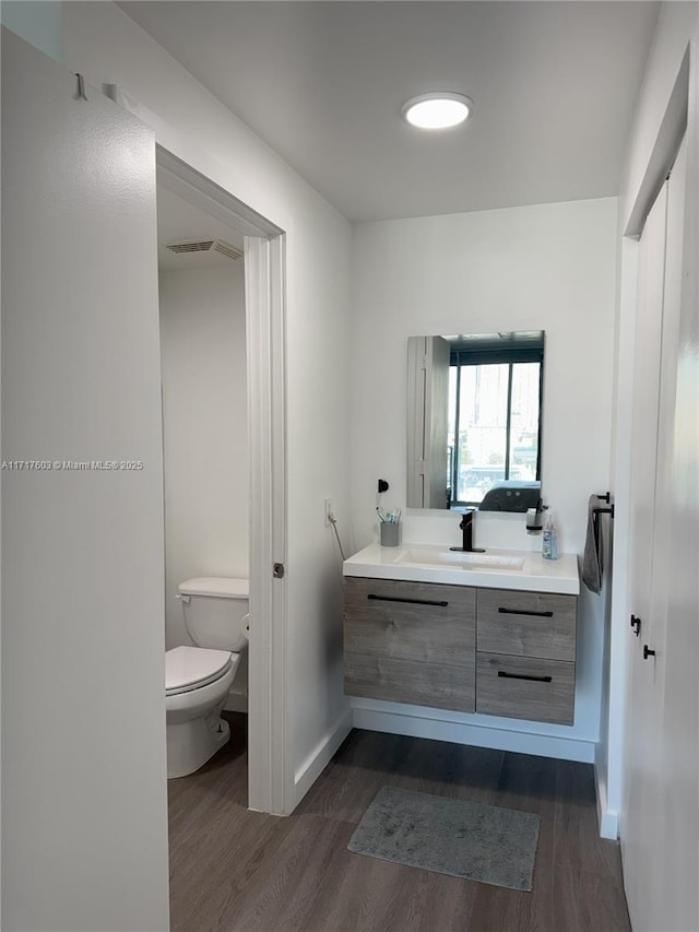 bathroom with toilet, hardwood / wood-style flooring, and vanity