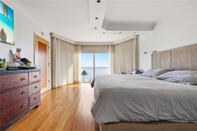 bedroom with a water view, crown molding, light hardwood / wood-style flooring, and access to outside