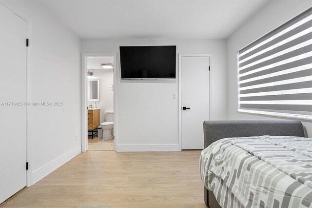 bedroom with light hardwood / wood-style floors and ensuite bath