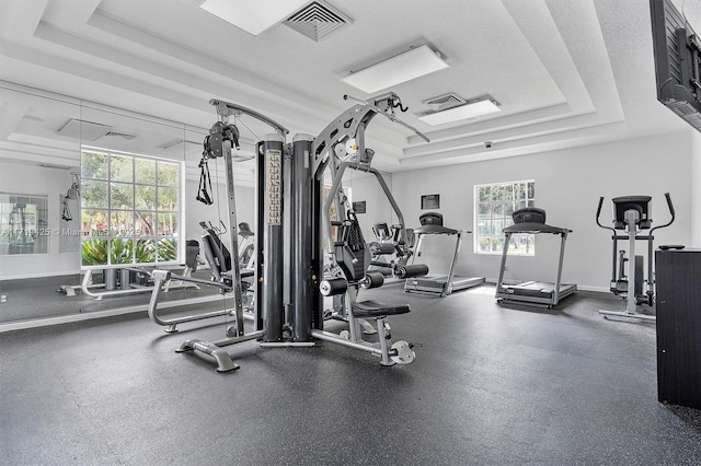 workout area featuring a tray ceiling and a textured ceiling