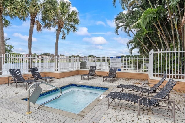 view of pool featuring a community hot tub, a water view, and a patio