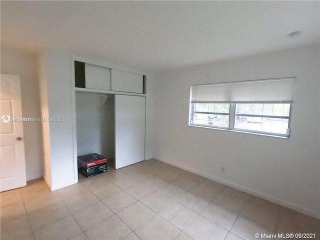 unfurnished bedroom featuring light tile patterned floors and a closet