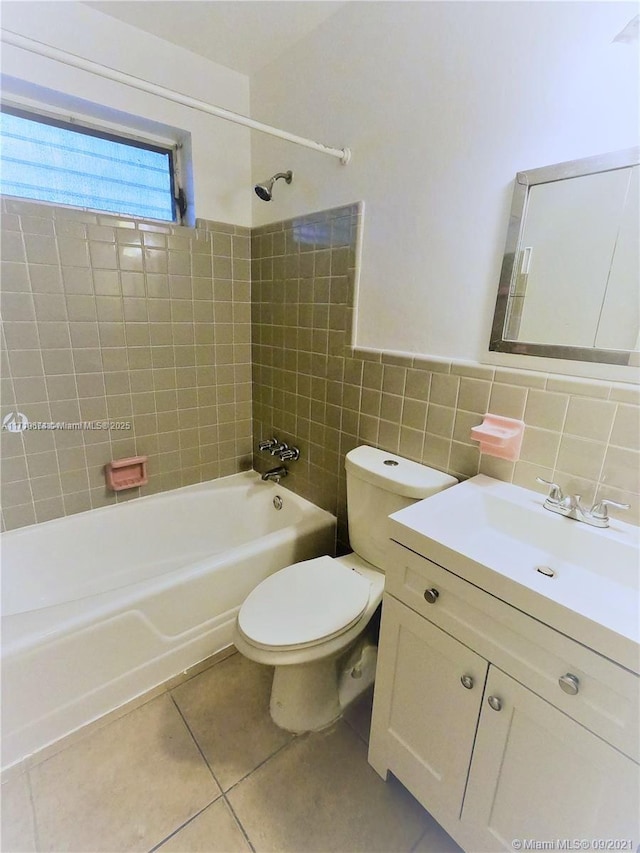 full bathroom with toilet, vanity, tile patterned flooring, tile walls, and tiled shower / bath combo