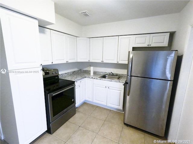 kitchen with white cabinets, appliances with stainless steel finishes, sink, light stone counters, and light tile patterned floors