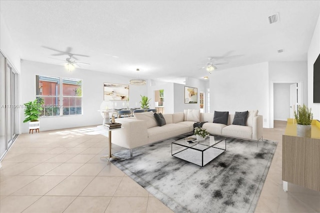 living room with a textured ceiling, ceiling fan, and light tile patterned flooring