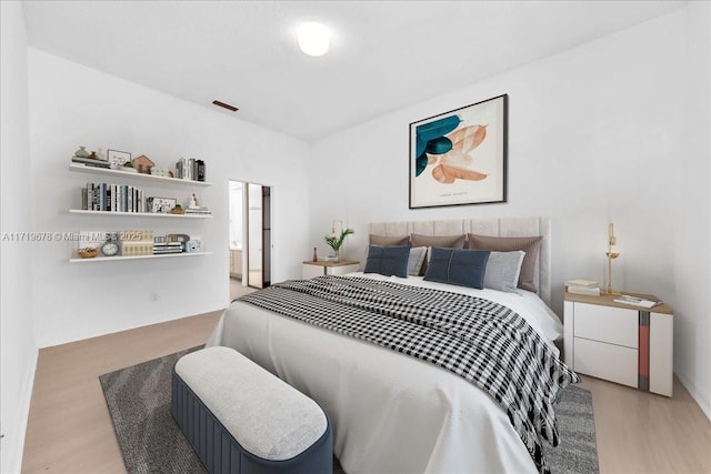 bedroom featuring light hardwood / wood-style flooring and ensuite bath