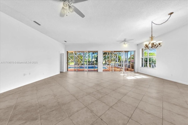 spare room featuring a textured ceiling, light tile patterned flooring, and ceiling fan with notable chandelier