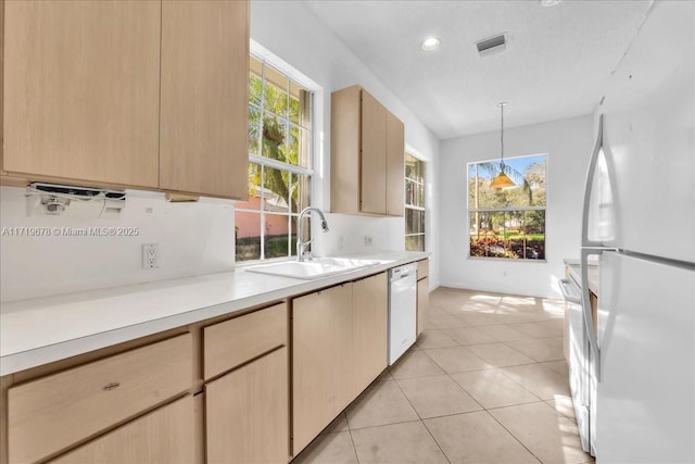 kitchen with white appliances, sink, light brown cabinetry, decorative light fixtures, and light tile patterned flooring