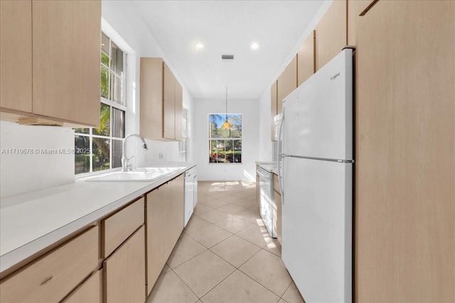 kitchen featuring pendant lighting, light brown cabinets, white appliances, and sink