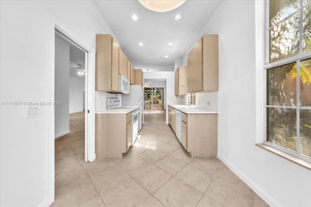 kitchen featuring light tile patterned flooring, white appliances, sink, and light brown cabinetry