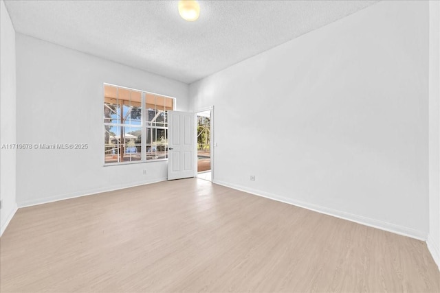 empty room featuring a textured ceiling and light hardwood / wood-style flooring