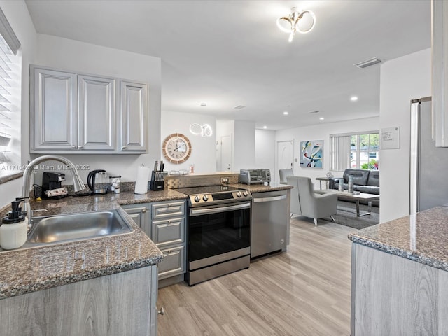 kitchen featuring gray cabinetry, appliances with stainless steel finishes, sink, and light wood-type flooring