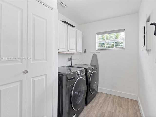 laundry area featuring cabinets, light hardwood / wood-style floors, and washer and dryer