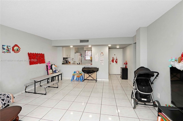 recreation room featuring light tile patterned floors and a textured ceiling