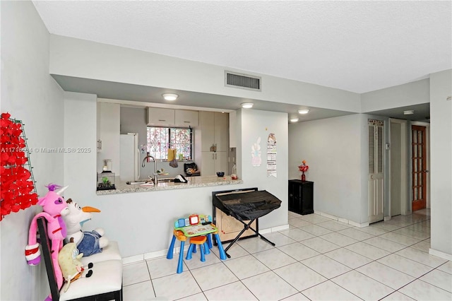 game room featuring a textured ceiling, light tile patterned floors, and sink