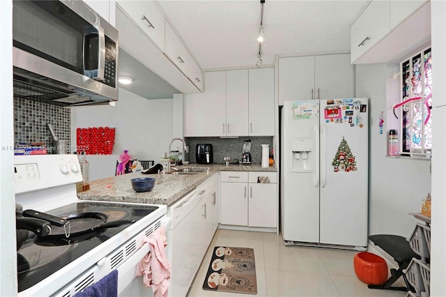 kitchen featuring rail lighting, backsplash, white appliances, white cabinetry, and light tile patterned flooring