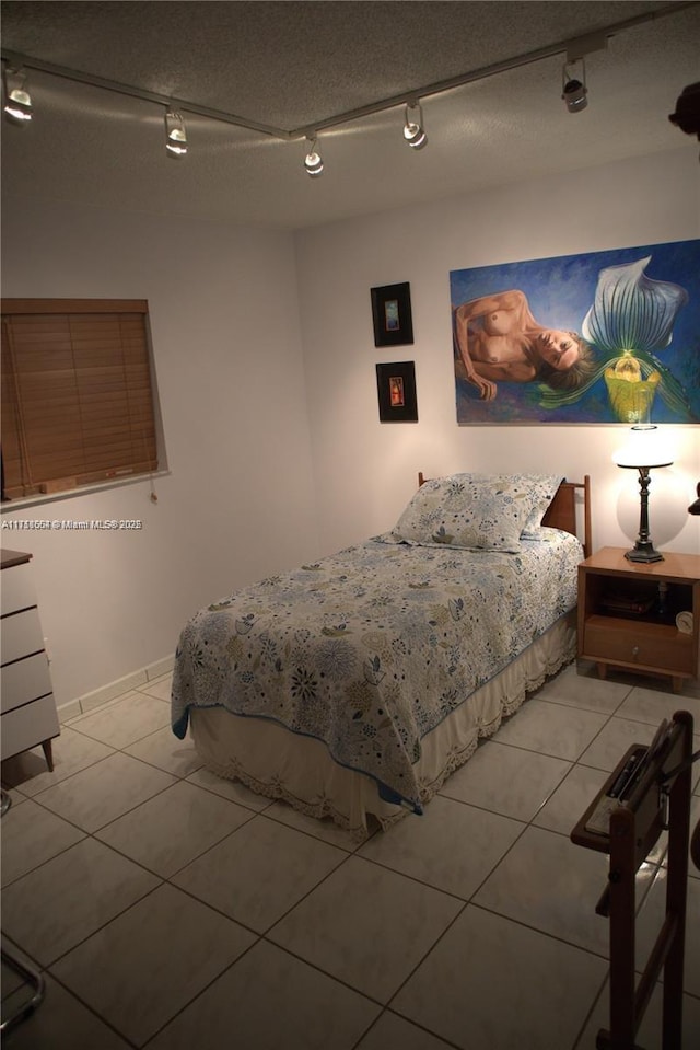 bedroom featuring a textured ceiling, track lighting, and light tile patterned flooring