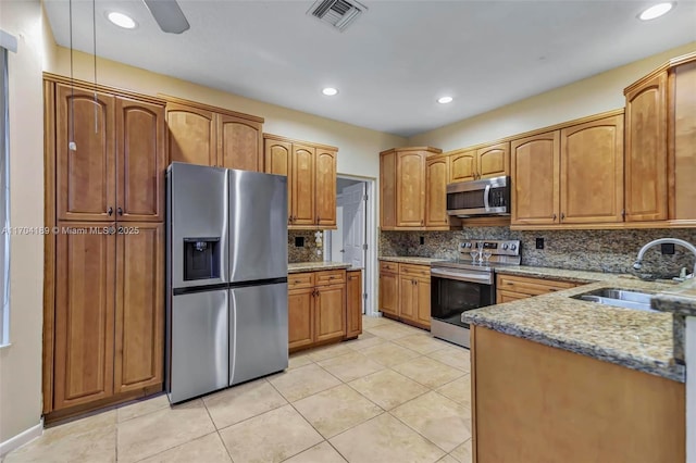 kitchen featuring sink, light tile patterned floors, appliances with stainless steel finishes, tasteful backsplash, and light stone counters