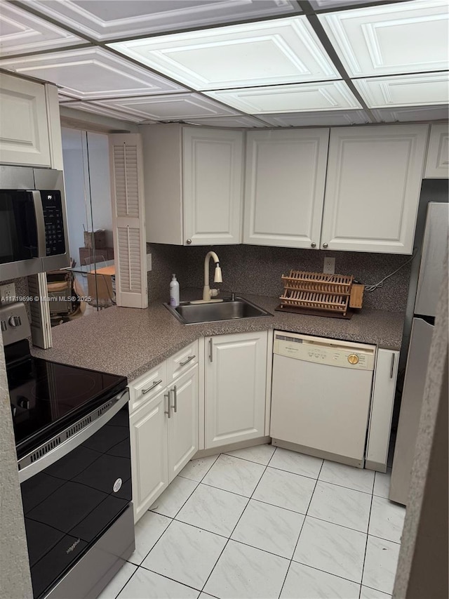 kitchen with light tile patterned floors, white cabinetry, sink, and appliances with stainless steel finishes