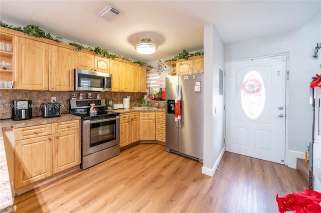 kitchen with decorative backsplash, light brown cabinets, stainless steel appliances, and light hardwood / wood-style floors