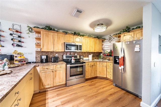 kitchen with decorative backsplash, light hardwood / wood-style floors, sink, and appliances with stainless steel finishes