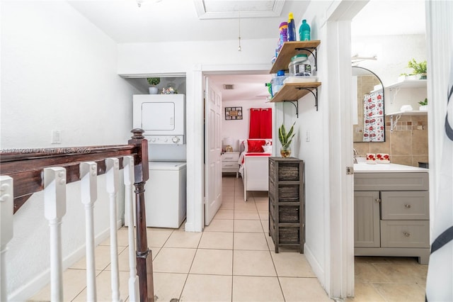 kitchen with gray cabinets, stacked washing maching and dryer, and light tile patterned floors