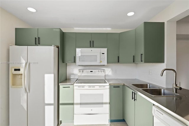 kitchen featuring backsplash, white appliances, sink, and green cabinetry