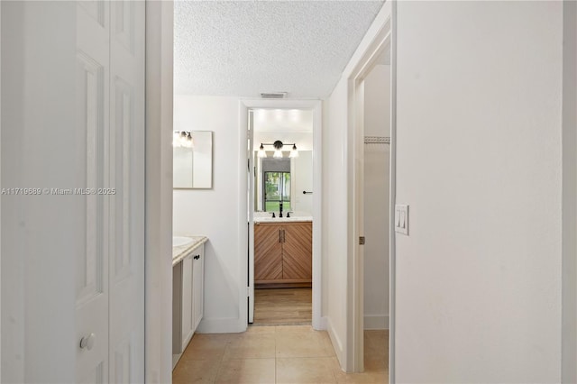 bathroom with tile patterned flooring, vanity, and a textured ceiling